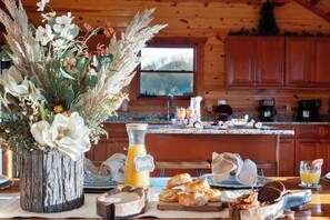 A rustic kitchen with wooden cabinets, a large window, and a breakfast setting with pastries and orange juice. - 6-Bedroom Mountain Cabin with Heated Indoor Pool & Game Room, Sleeps 14 (Sevierville)