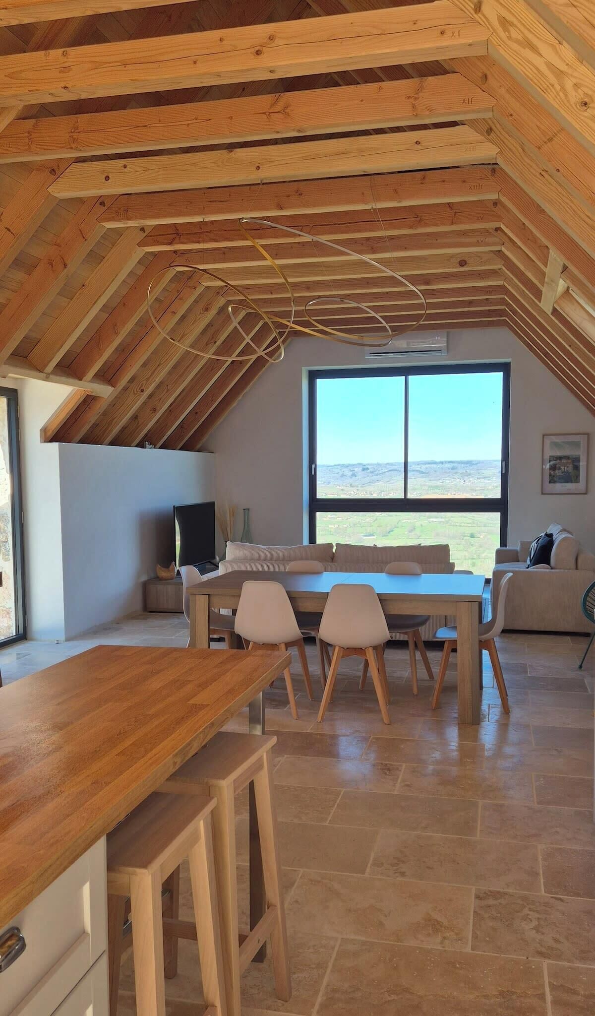 Ein geräumiger Dachbodenraum mit einem großen Fenster und Blick auf die Landschaft.