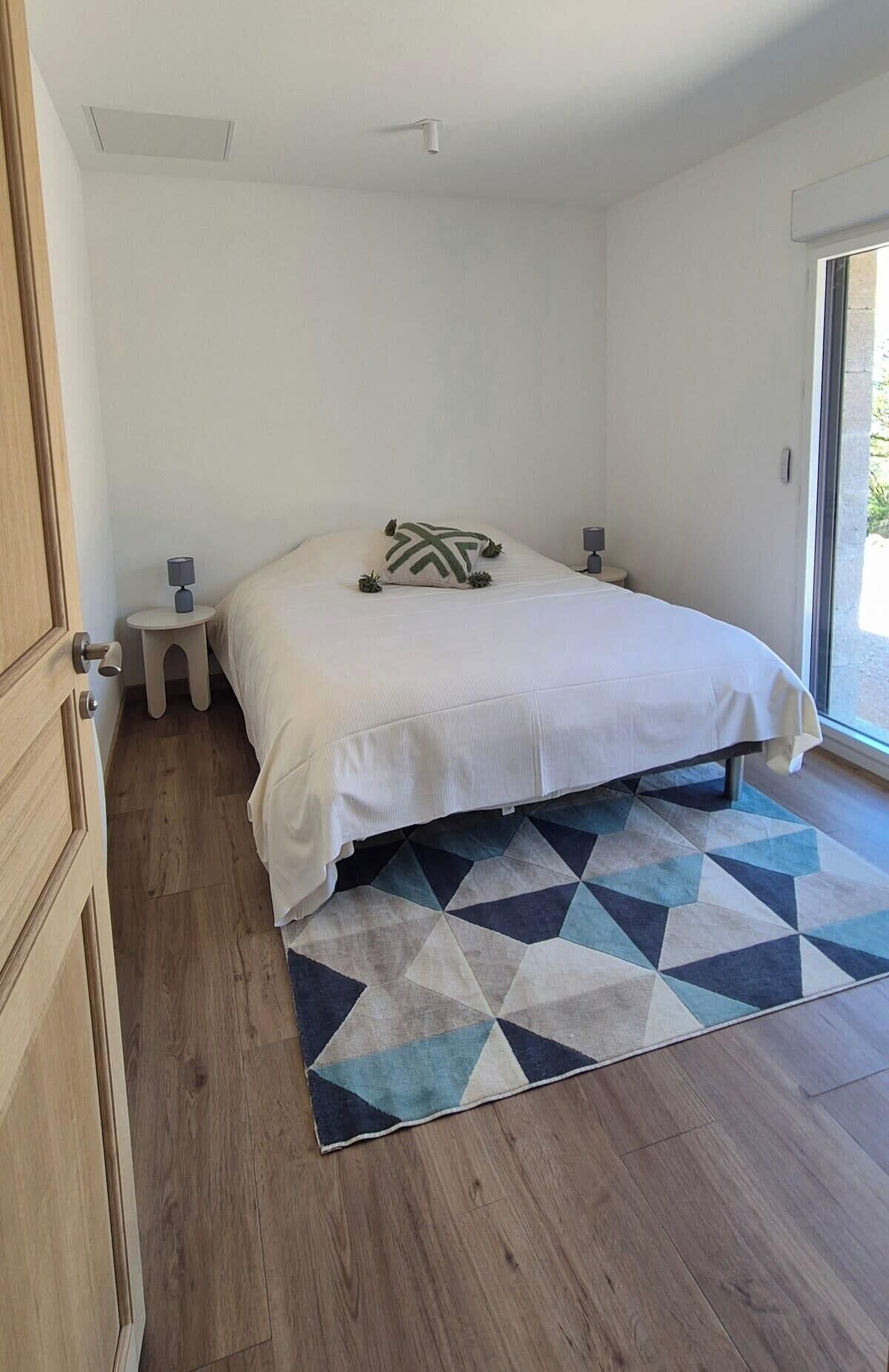 Ein Schlafzimmer mit einem Bett, einem Nachttischchen, einem Teppich und einer Tür.