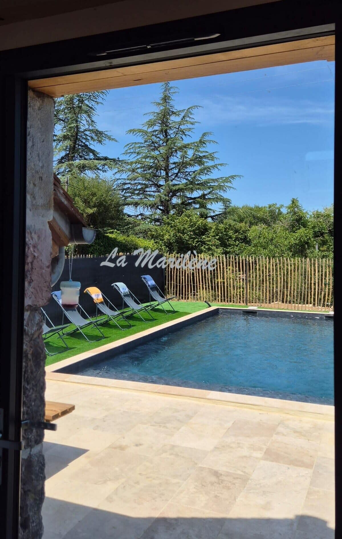 Una piscina con sillones de descanso y una terraza de madera.