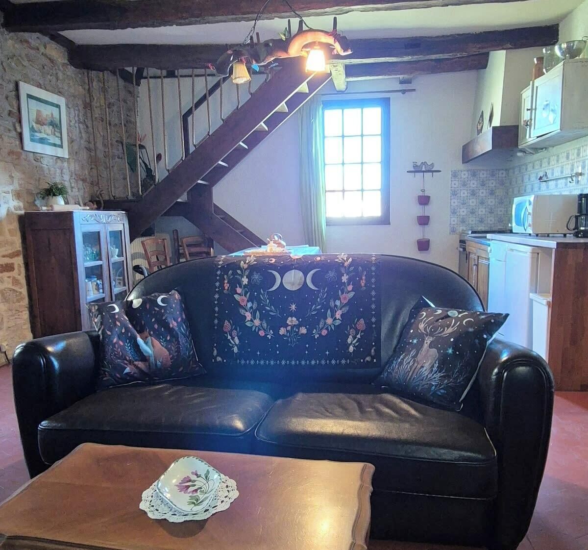 Een gezellige woonkamer met een leren bank, een houten salontafel en een trap naar een verdieping erboven.