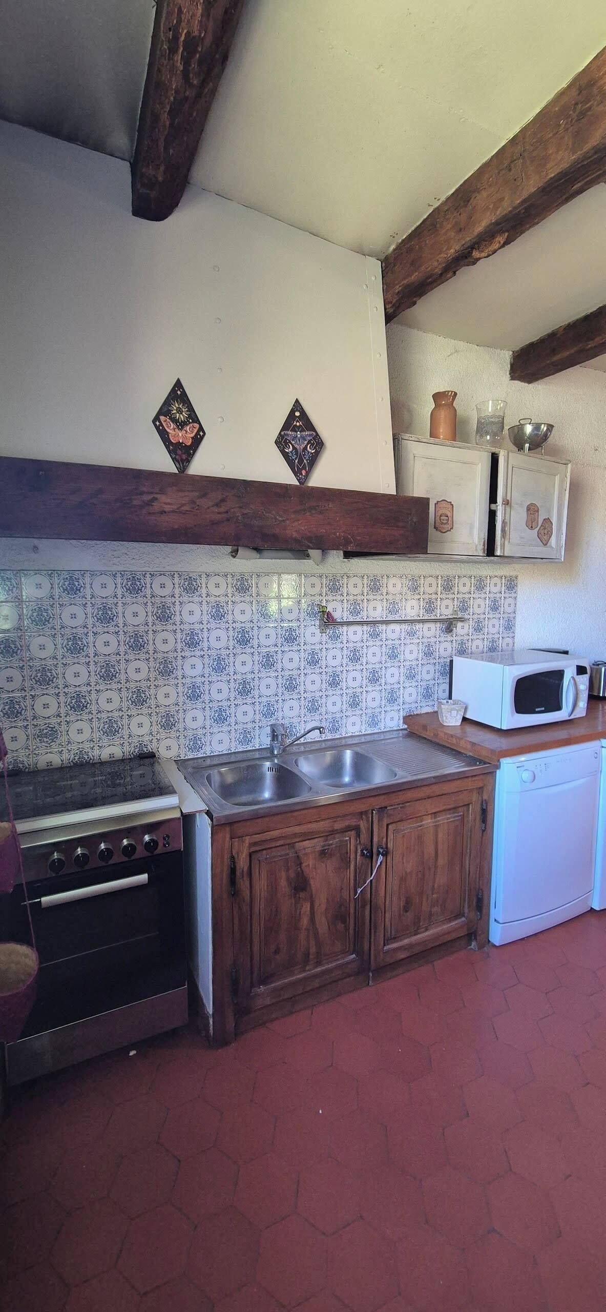A kitchen with a stove, sink, and microwave. There are wooden cabinets and a tiled backsplash.