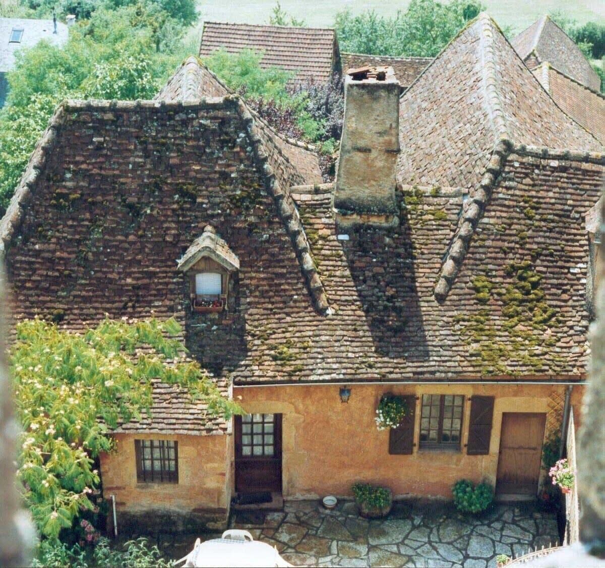 A traditional stone house with a steeply pitched roof, a small window, and a door.