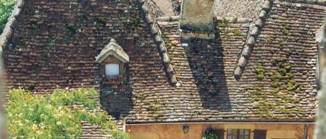 A traditional stone house with a steeply pitched roof, a small window, and a door.