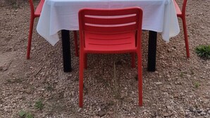 An outdoor dining table set with white tablecloth, red chairs, and a basket of bread and flowers. - l'Ardoise, Maison au pied du château de Castelnau (Prudhomat)