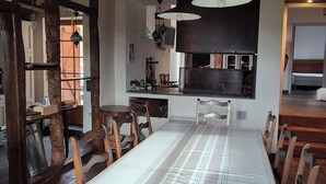 A long dining table with chairs, wooden beams on the ceiling, and pendant lights. - l'Ardoise, Maison au pied du château de Castelnau (Prudhomat)