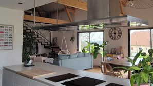 Une cuisine moderne dotée d’un îlot central, d’appareils électroménagers intégrés et d’un escalier menant à un niveau supérieur.