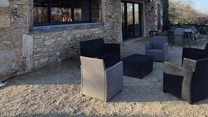 A stone building with a covered outdoor seating area and wicker furniture. - La Bergerie de la Borie, piscine, près Rocamadour (Miers)