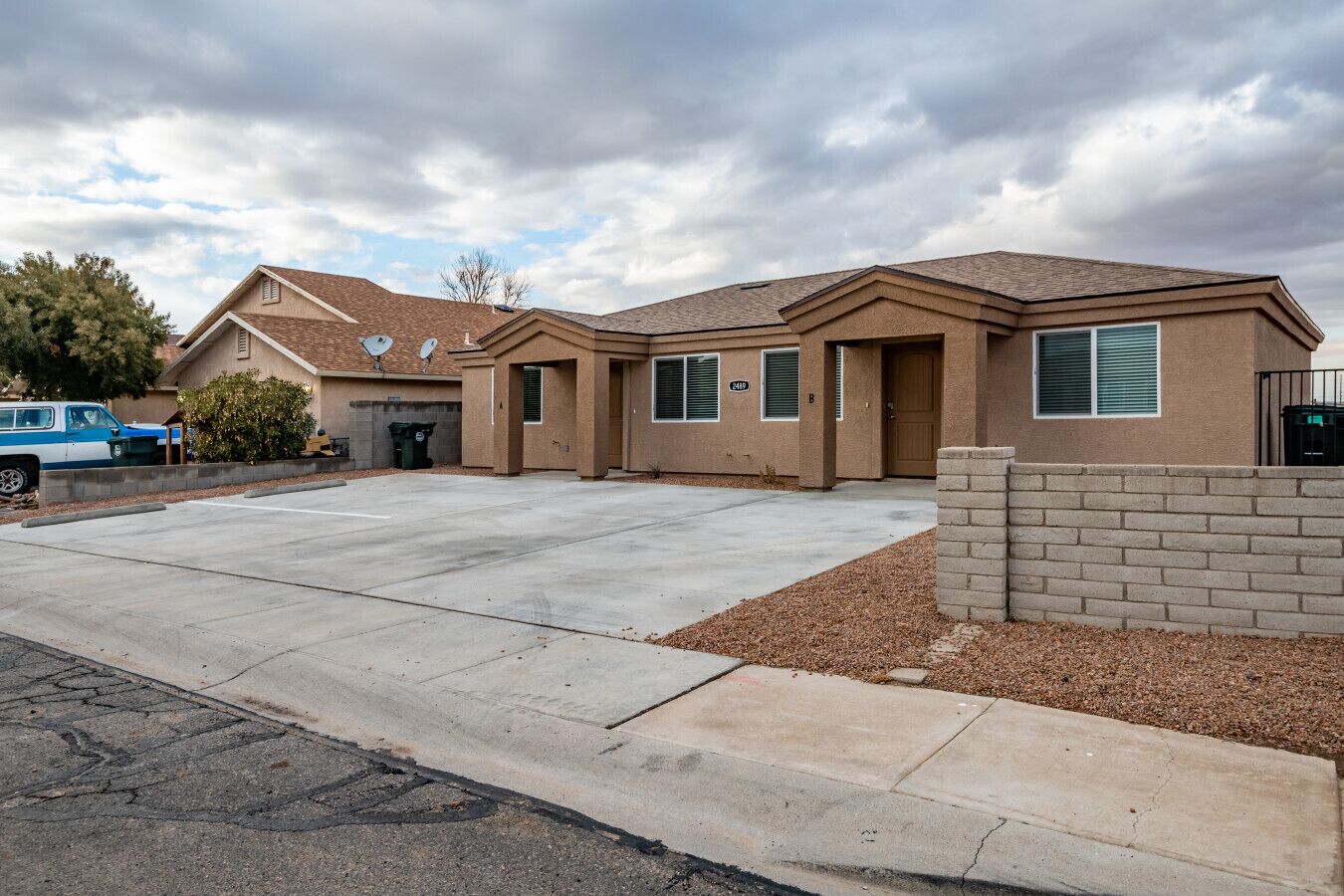 A two-story house with a driveway, a brick wall, and a satellite dish.