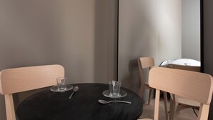 A round table with a black tablecloth, two wooden chairs, and a glass and spoon on the table.