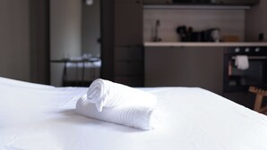 A neatly made bed with a rolled white towel in a modern hotel room.