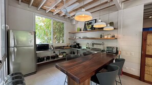 A modern kitchen with a central island, stainless steel appliances, and wooden shelves. - Bungalow in "marAmar" compound, Santa Teresa Beach. Walk everywhere! (Santa Teresa)