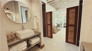 Uma casa de banho com um espelho grande, uma pia e um porta-toalhas.