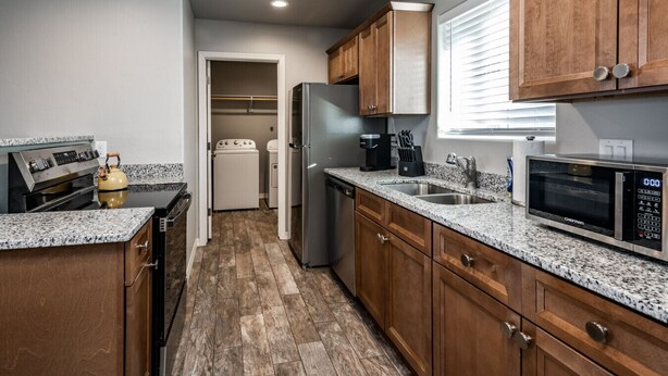 A modern kitchen with granite countertops, stainless steel appliances, and wooden cabinets. - Modern Luxury Retreat | Brand-New Build | Pet-Friendly (Kingman)