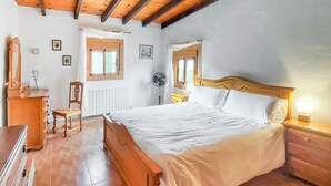 A bedroom with a wooden bed, a chair, a desk, and a radiator.
