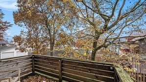 A wooden bench with a metal railing, surrounded by autumn leaves and a tree with yellow leaves. -  3-bedroom townhome in Kansas City (Kansas City)