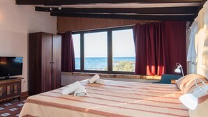 A hotel room with a large bed, a TV, a window with curtains, and a view of the sea. - 3 bedroom nice home in Colonia de Sant Pere (Colonia de Sant Pere)