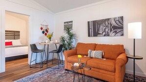 Een moderne woonkamer met een bank, stoelen, een bijzettafeltje en een vloerlamp.
