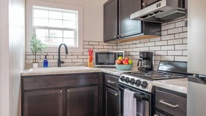 Una cocina con armarios oscuros, un microondas, una estufa y un lavamanos.