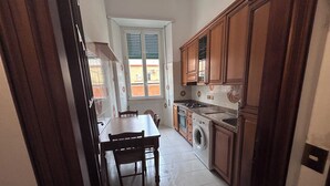 Une cuisine compacte comprenant une table à manger, des chaises, un lave-linge et des placards en bois.