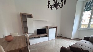 Un salon avec un canapé, un téléviseur et une table à manger entourée de chaises.