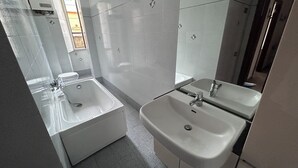 Une salle de bain moderne avec une baignoire, deux lavabos et une douche.