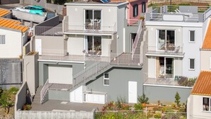 Ein mehrgeschossiges Wohngebäude mit Balkonen, einer sichtbaren Treppe und einer kleinen Gartenanlage.