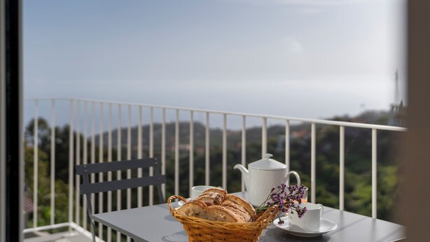 Ein Balkon mit einem für Tee gedeckten Tisch, einem Brotkorb und Blick auf die Hügel.