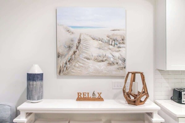A kitchen with a white countertop, a painting of a snowy landscape, a decorative wooden sign, and a blue and white vase. - 4-Bedroom Panama City Beach Home with Private Heated Pool (Panama City Beach)