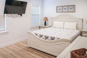 A bedroom with a bed, a television mounted on the wall, and a window with blinds. - 4-Bedroom Panama City Beach Home with Private Heated Pool (Panama City Beach)