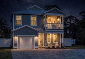 Una casa a due piani con garage, un balcone e un ingresso ben illuminato.
