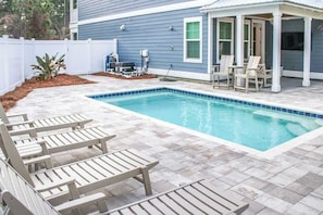 A swimming pool with lounge chairs and a covered seating area. - 4-Bedroom Panama City Beach Home with Private Heated Pool (Panama City Beach)