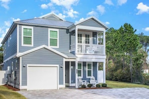 A two-story house with a garage, a balcony, and a covered porch area. - 4-Bedroom Panama City Beach Home with Private Heated Pool (Panama City Beach)