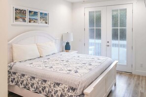 Un dormitorio con cama, mesita de noche, lámpara y puerta con paneles de vidrio esmerilado.