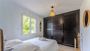 Quarto com cama, janela e porta com vista para o verde lá fora.