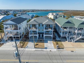 A multi-story residential building with balconies, a driveway, and a view of a body of water. - Stunning 8BR Luxury Property Just Steps to the Beach, Pier & Restaurants! (Wrightsville Beach)