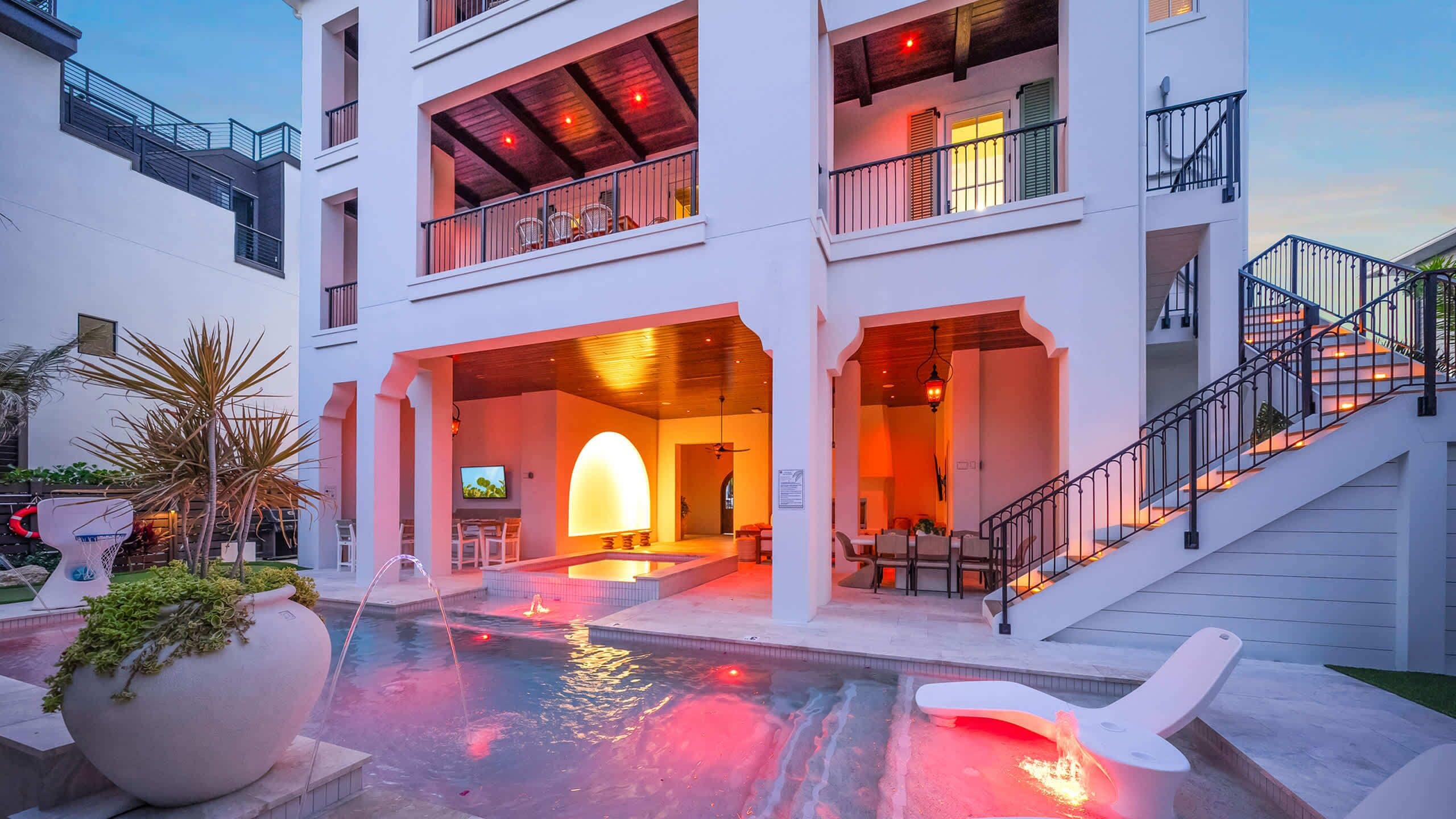 Un hotel de varios pisos con piscina, asientos al aire libre y una escalera.