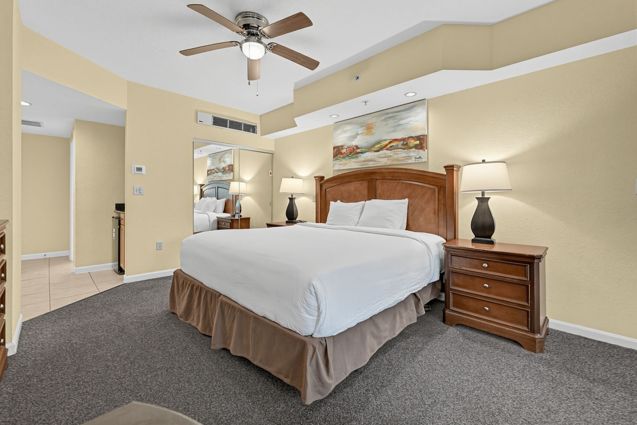 King bed with a timber headboard, soft bedding, and considered lighting