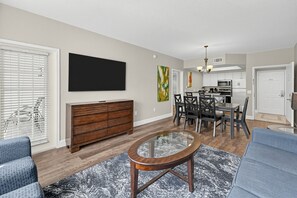Living room with large TV, dining area, and seating. - Near Disney! 1BR Deluxe Condo w/ Full Kitchen (Kissimmee)