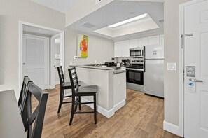 Kitchen area with bar stools and modern appliances. - Near Disney! 1BR Deluxe Condo w/ Full Kitchen (Kissimmee)