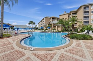 Relax by the tranquil pool under a stunning sunlight with shaded seating. - Near Disney! 1BR Deluxe Condo w/ Full Kitchen (Kissimmee)