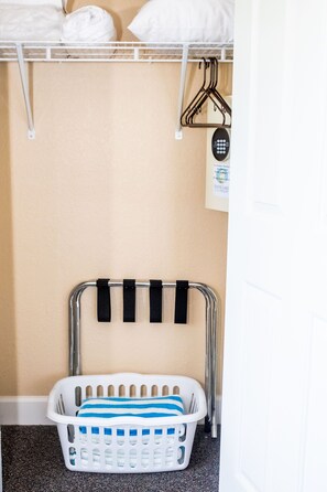 A laundry basket with a striped towel, a metal rack with hangers, and a sign on the wall. - Near Disney! 1BR Deluxe Condo w/ Full Kitchen (Kissimmee)