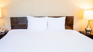 A neatly made bed with white linens, a wooden headboard, and bedside lamps. - Near Disney! 1BR Deluxe Condo w/ Full Kitchen (Kissimmee)
