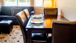 A dining area with a table set for two, a sofa, and a lamp. - Near Disney! 1BR Deluxe Condo w/ Full Kitchen (Kissimmee)