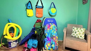 A room with teal walls, a wicker chair with a cactus-patterned pillow, and various bags and equipment against the wall. - #2 Cozy 1-bedroom apartment in Cahuita w/ AC, parking-near beach, national park (Cahuita)