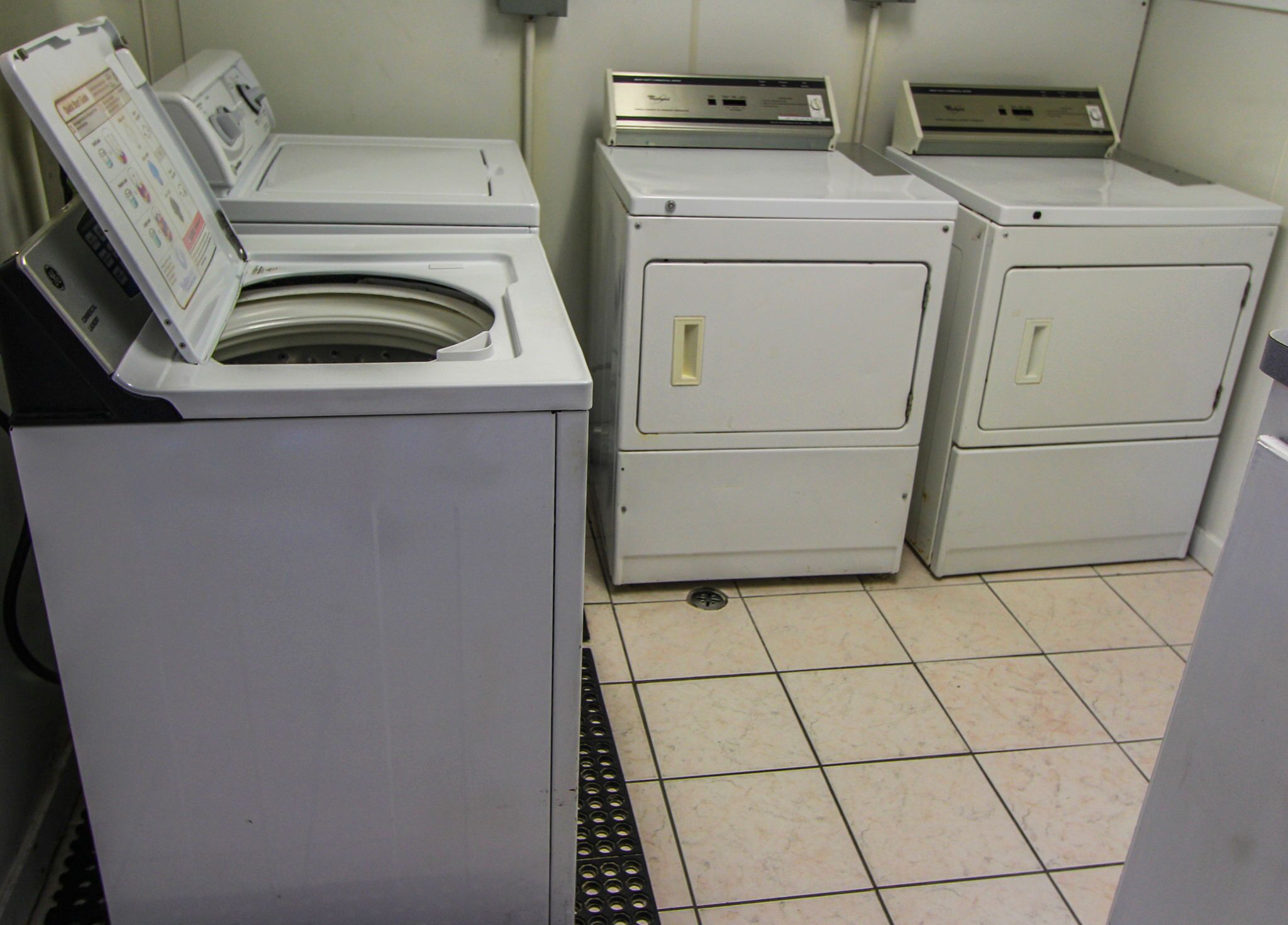 Een wasserette met drie wasmachines en een droger.
