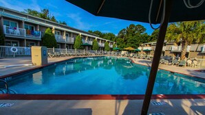 A swimming pool with lounge chairs and umbrellas, surrounded by a hotel with balconies and trees. - 2BR Loft Villa w/ Jetted Tub + Resort Access! (Hilton Head Island)