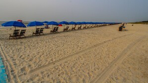 A beach with rows of blue umbrellas and wooden lounge chairs aligned along the sand. - 2BR Loft Villa w/ Jetted Tub + Resort Access! (Hilton Head Island)