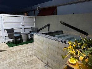 Een buitenzwembad met een zithoek en een wand met open structuur.