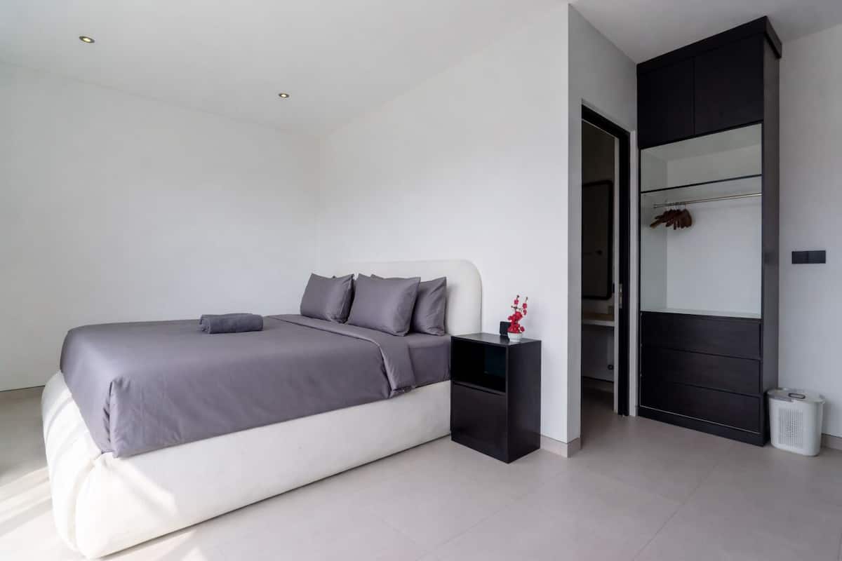 Quarto moderno com cama, mesa de cabeceira e guarda-roupa.